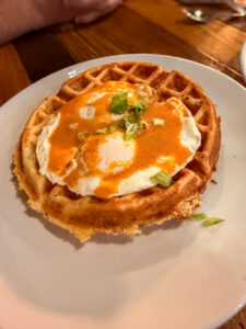 Deep South Waffle dish at Buffalo Breakfast Co topped with eggs and chipotle hollandaise