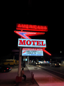 Americana Motel Route 66 neon sign at dusk