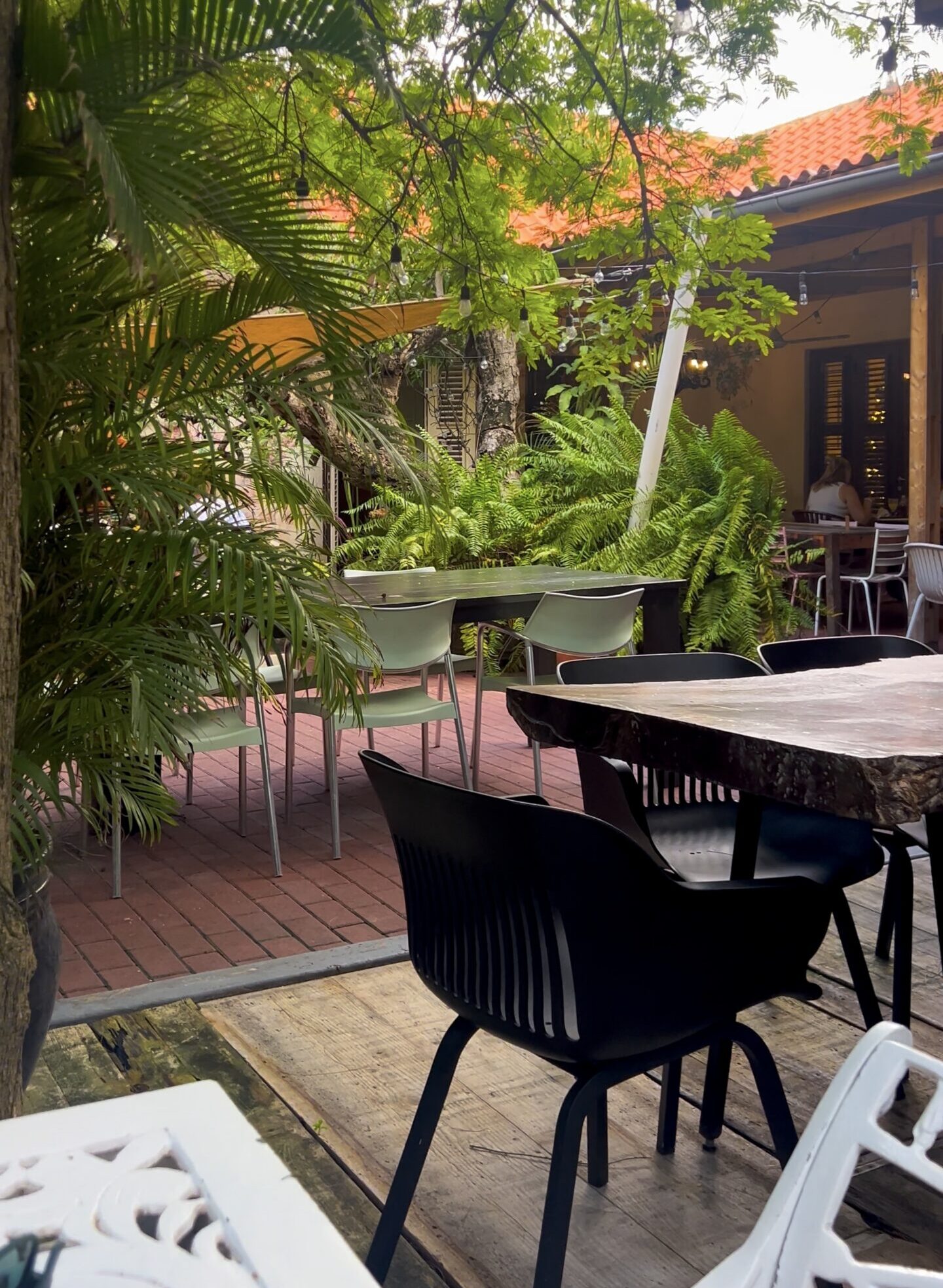 Number Ten Curaçao review showing garden seating with greenery and shaded tables