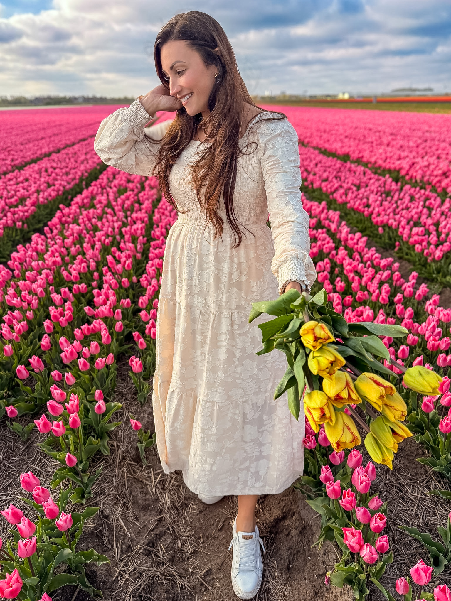 Woman wearing a cream dress in colorful flower rows for what to wear in the tulip fields Netherlands