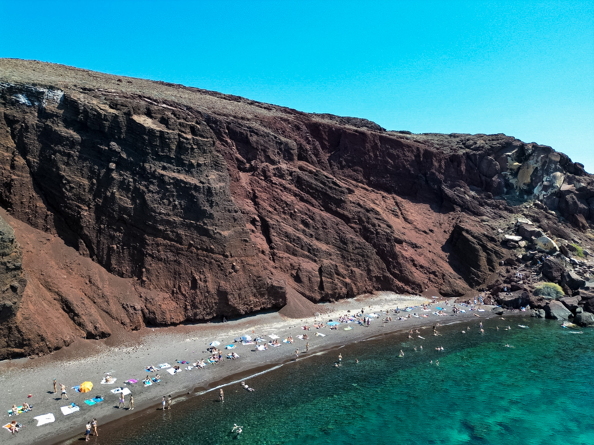 Red volcanic cliffs at Red Beach in Santorini seen from a boat