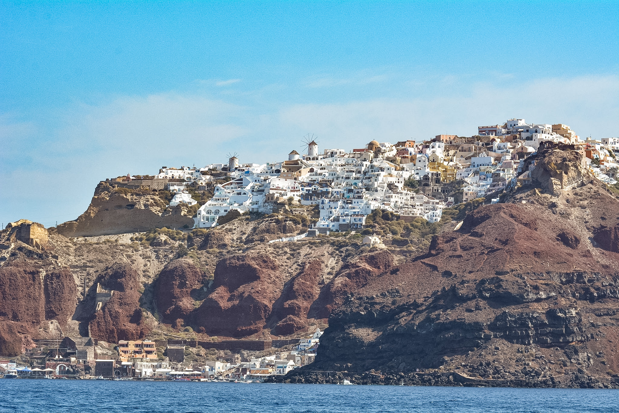 White buildings of Oia perched above Ammoudi Bay as seen from the water